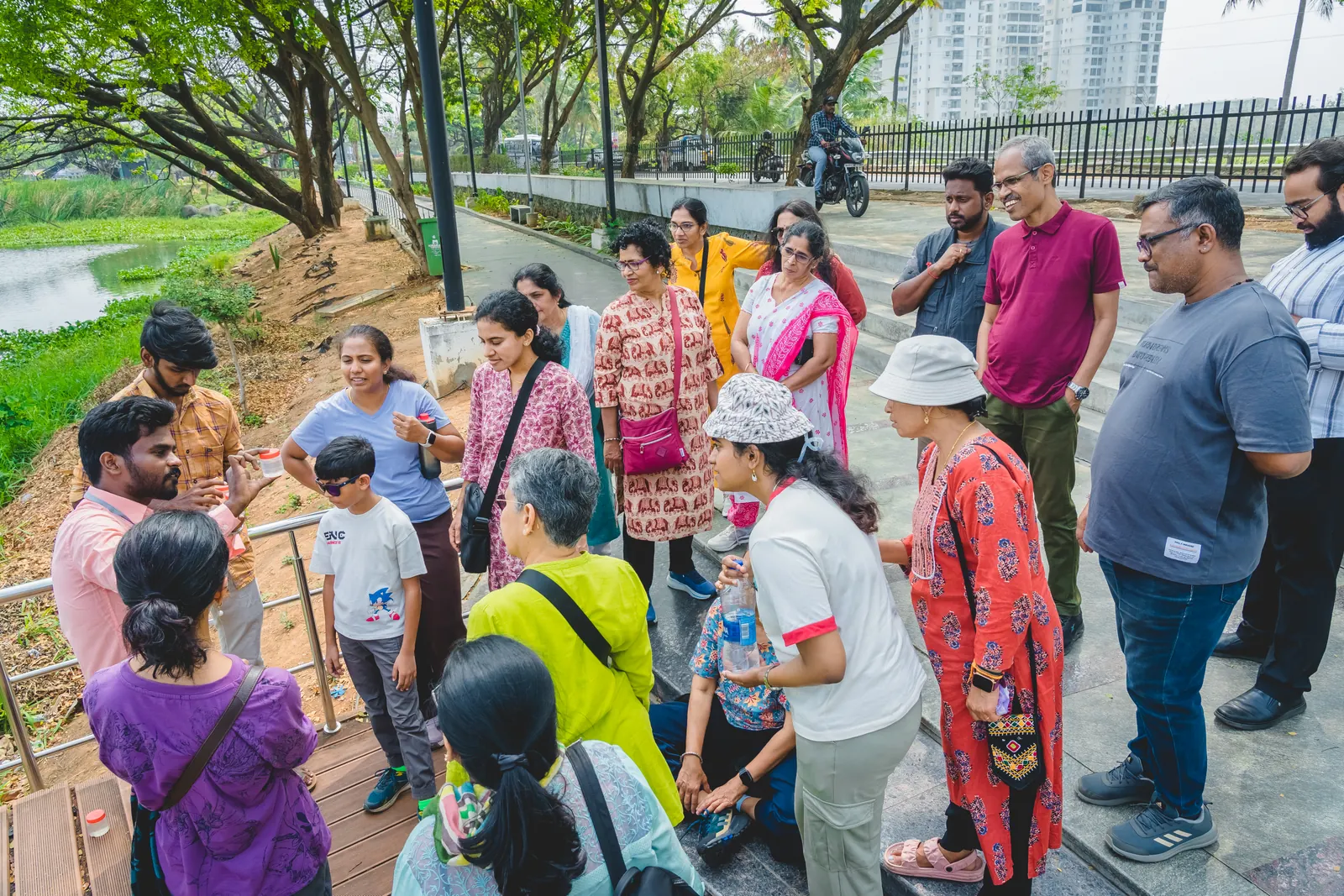 A guided group gathered beside a city lake at the start of a morning walk