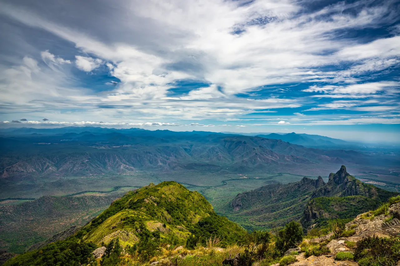 Green forested ridges of the Western Ghats under a wide cloudy sky